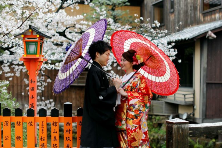 A couple chats while posing for a photo with blooming cherry blossoms in Kyoto