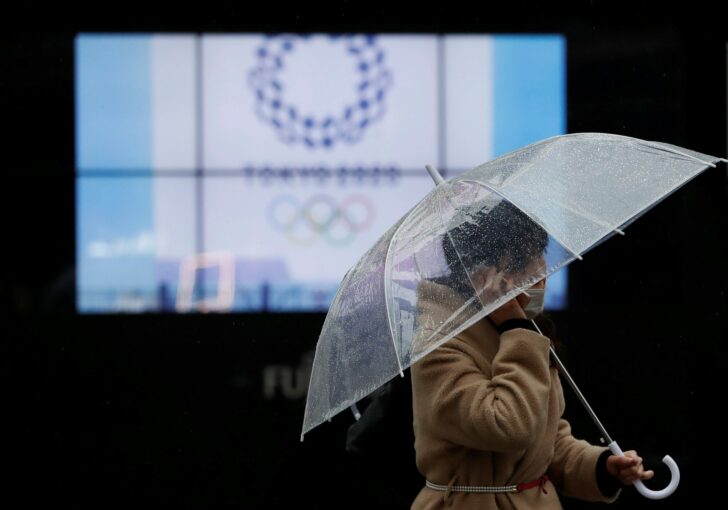 A passerby wearing a protective face mask walks past a display showing the logo of Tokyo 2020 Olympic Games, amid the coronavirus disease (COVID-19) outbreak in Tokyo