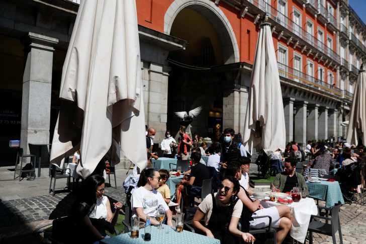 Pigeon flies over people sitting at a terrace at Plaza Mayor square, in Madrid