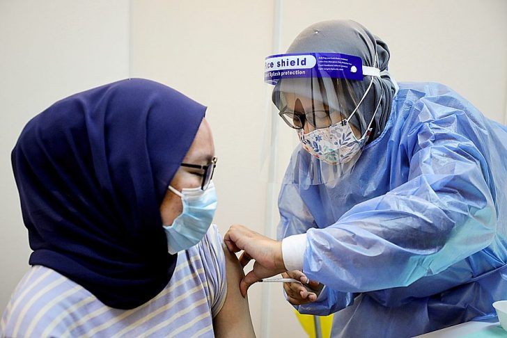 A woman receives a dose of AstraZeneca's COVID-19 vaccine at a vaccination centre in Kuala Lumpur