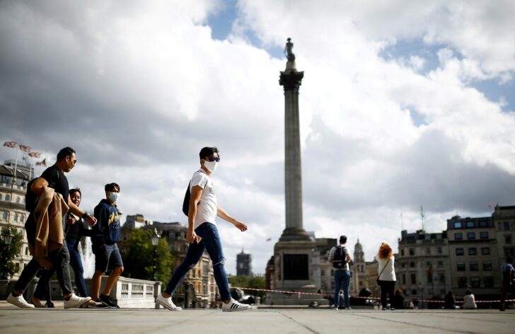 FILE PHOTO: People wearing protective face masks walks through Trafalgar Square, amid the coronavirus disease (COVID-19) outbreak, in London