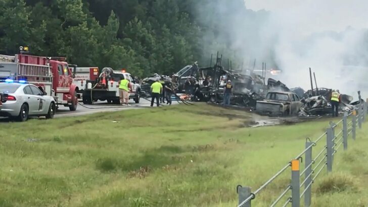 Emergency personnel work at the accident site as smoke rises from the wreckage after about 18 vehicles slammed together on a rain-drenched Alabama highway during Tropical Storm Claudette, in Butler County, Alabama