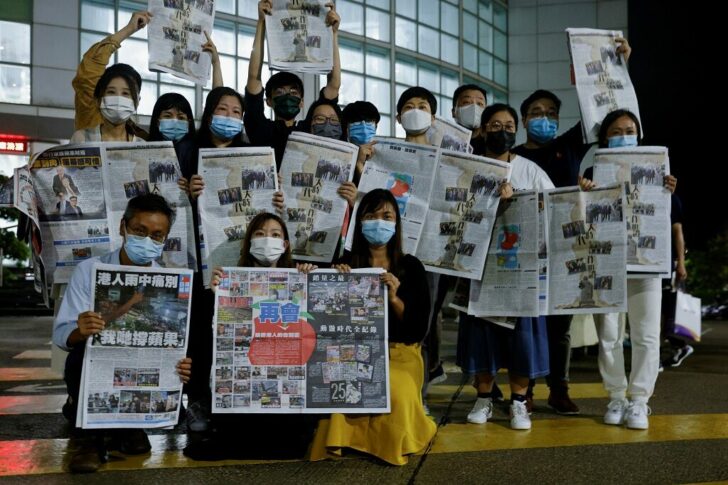Staff members of Apple Daily and its publisher Next Digital pose with the final edition of Apple Daily at its headquarters in Hong Kong