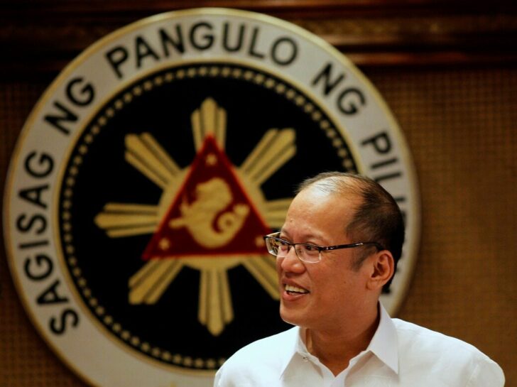 FILE PHOTO - Philippine President Benigno Aquino smiles in front of a presidential seal during a government's oral immunization program for poor families at the presidential palace in Manila