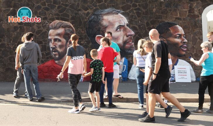 England fans pose for a photograph in front of a giant mural created by street artist Nathan Parker