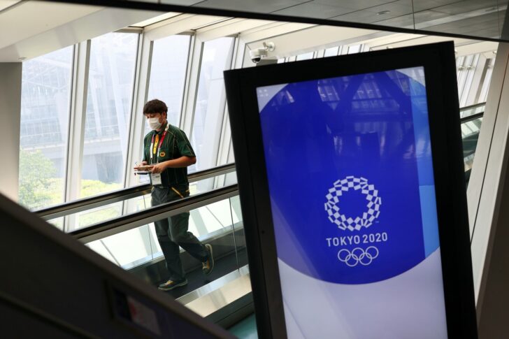 A man wearing a face mask walks past Tokyo 2020 Olympic Games signage at the Main Press Center in Tokyo