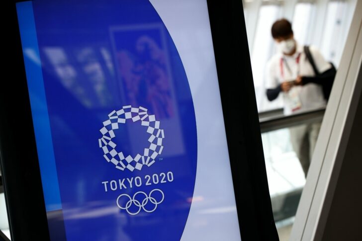 A man wearing a face mask walks past Tokyo 2020 Olympic Games signage at the Main Press Center in Tokyo