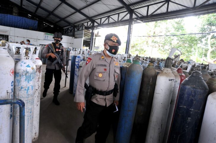Police officers walk as they guard the oxygen distribution at a refill factory amid the coronavirus disease (COVID-19) outbreak in Mengwi, Badung, Bali