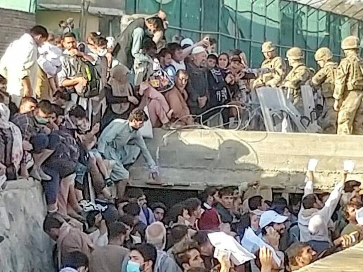 Security personnel assist with evacuation of people waiting outside the airport in Kabul
