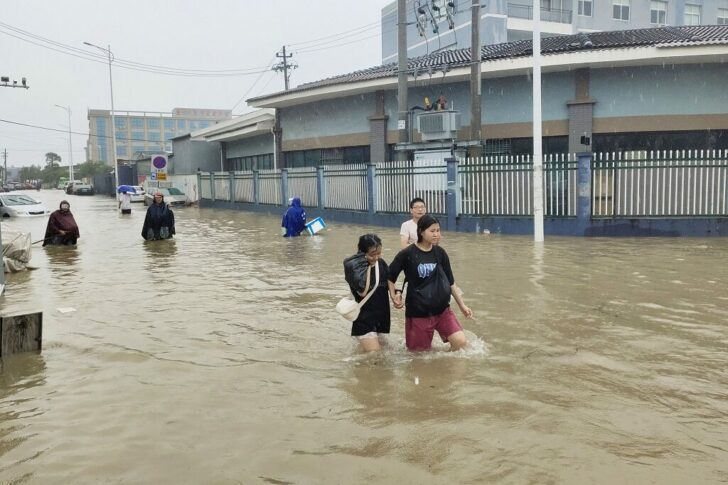 People wade through a flooded road in Dongqiao town of Ningbo, Zhejiang province, as Typhoon In-fa lashes the coastal regions