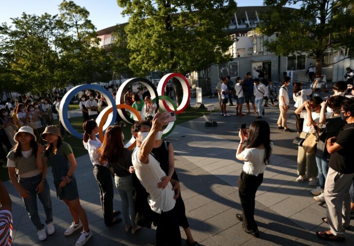 People take photos with an Olympic rings monument outside the National Stadium Tokyo