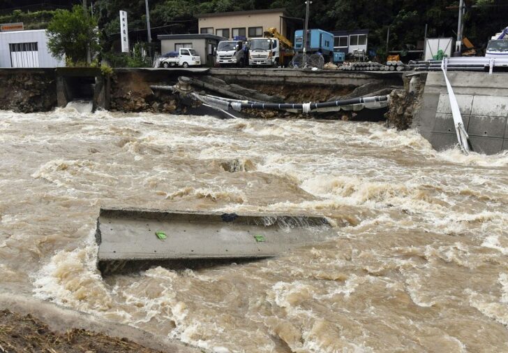 A road is damaged by the swollen Suzuhari river caused by a heavy rain in Hiroshima