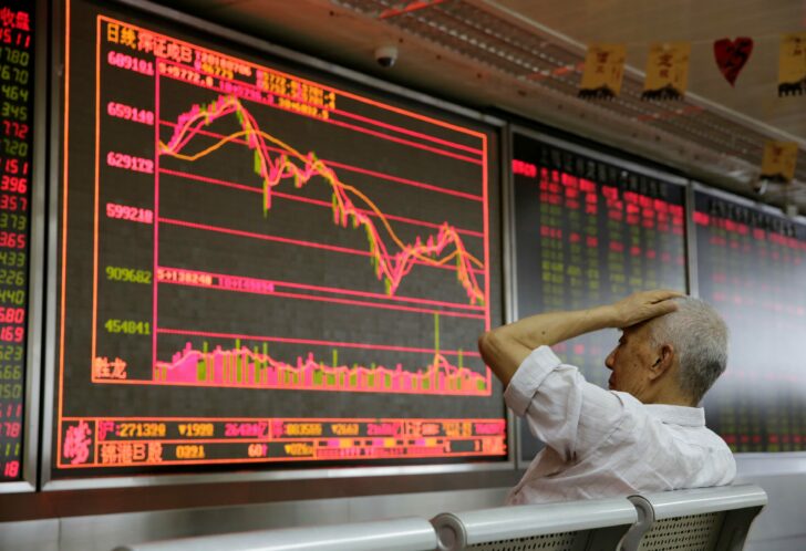An investor looks at a board showing stock information at a brokerage office in Beijing