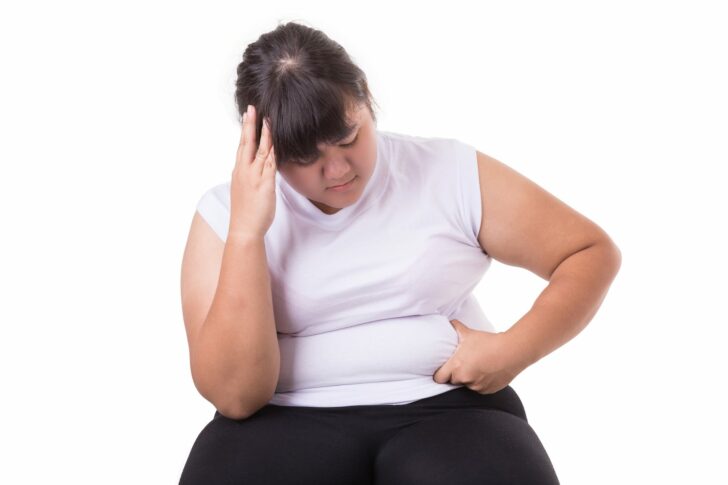 Fat Asian woman wear white t-shirt worried about her body size isolated on white