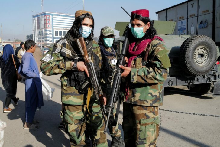 Bader, 21, a Taliban fighter, and his comrade pose for a photograph at the market in Kabul