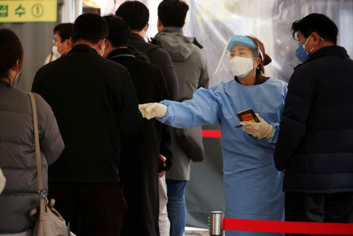 FILE PHOTO: Health worker directs people arriving to undergo COVID-19 tests at testing site in Seoul