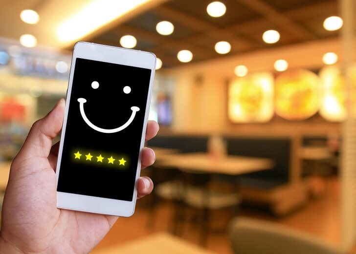 Woman is pressing face emoticon on virtual touch screen at smartphone.