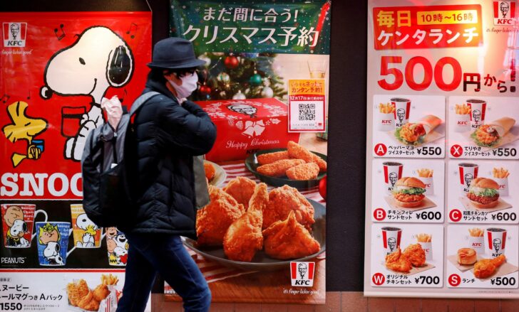 FILE PHOTO: A man wearing a protective mask, amid the coronavirus disease outbreak, walks past a Kentucky Fried Chicken (KFC) restaurant in Tokyo