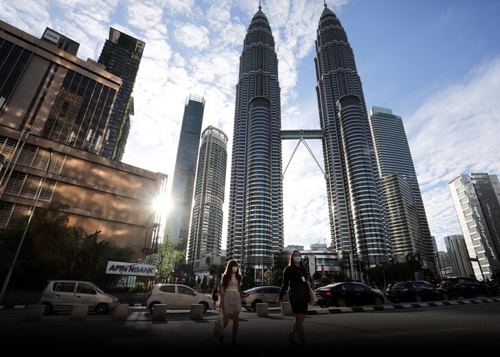 FILE PHOTO: People wearing protective masks cross a street in front of Petronas Twin Towers, amid the coronavirus disease (COVID-19) outbreak in Kuala Lumpur