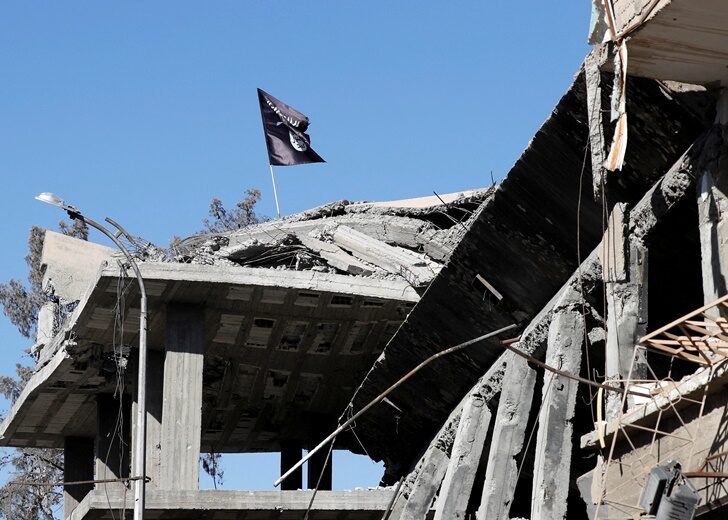 FILE PHOTO: A flag of Islamic State militants is pictured above a destroyed house near the Clock Square in Raqqa