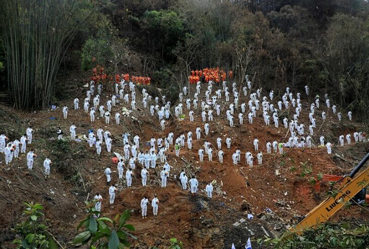 Rescue workers stand in a silent tribute to mourn plane crash victims in Wuzhou