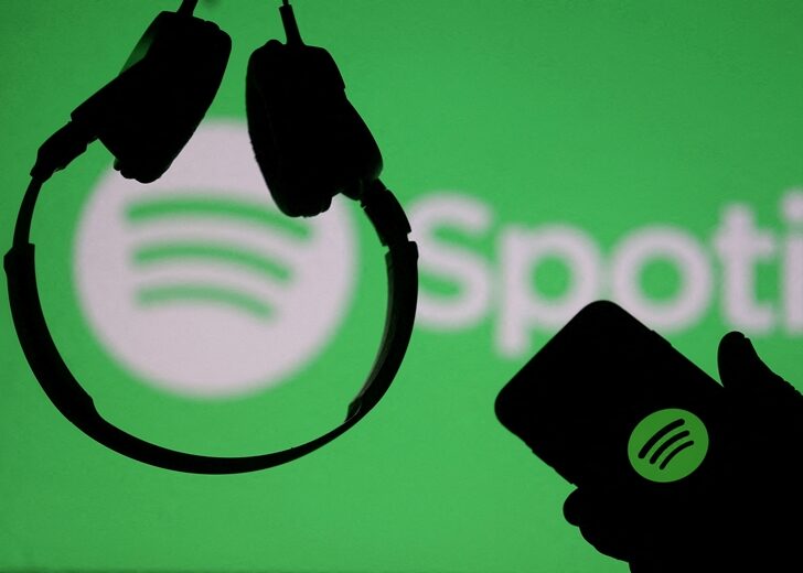 FILE PHOTO: A smartphone and a headset are seen in front of a screen projection of Spotify logo, in this picture illustration