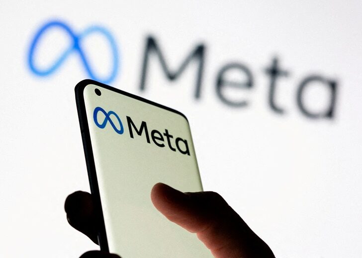 FILE PHOTO: Woman holds smartphone with Meta logo in front of a displayed Facebook's new rebrand logo Meta in this illustration picture