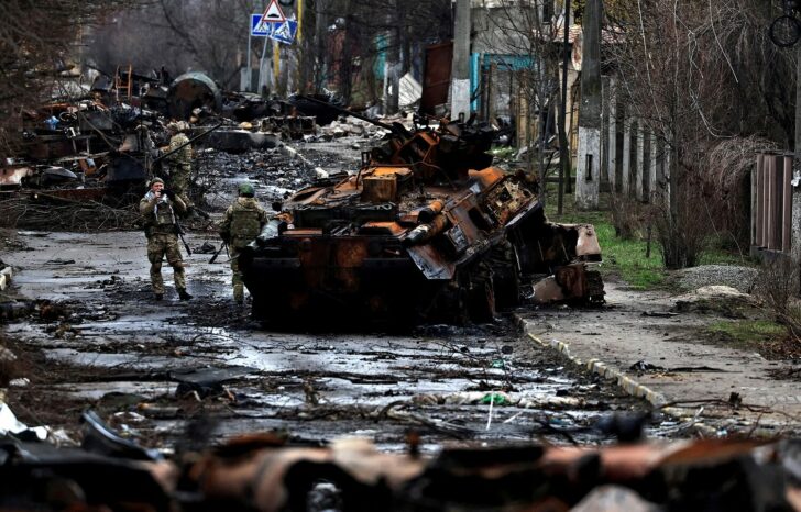 FILE PHOTO: A soldier takes a photograph of his comrade as he poses beside a destroyed Russian tank and armoured vehicles, amid Russia's invasion on Ukraine in Bucha, in Kyiv region