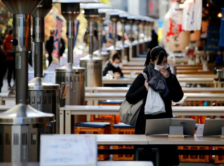FILE PHOTO: A woman wearing protective a face mask is seen at an open-air restaurant amid coronavirus disease (COVID-19) outbreak in Tokyo