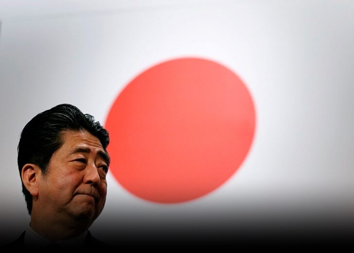 FILE PHOTO: Japan's Prime Minister Abe stands in front of Japan's national flag after his ruling LDP annual party convention in Tokyo