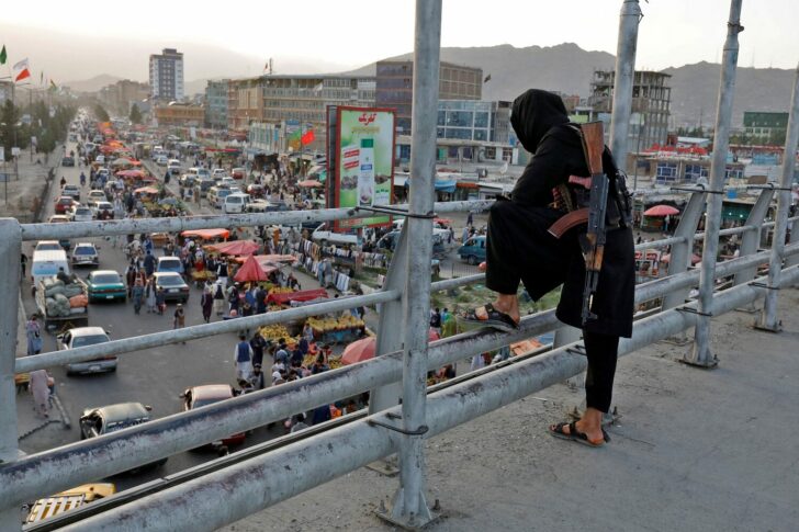 A Taliban fighter stands guard on a bridge in Kabul
