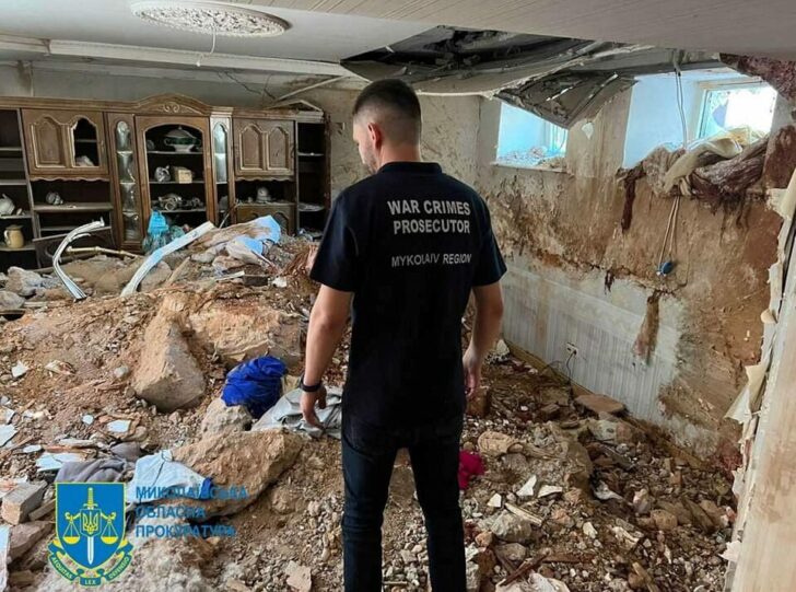 A war crimes prosecutor examines the damage in a destroyed building in Mykolaiv