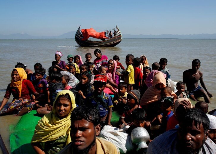 FILE PHOTO: Rohingya refugees sit on a makeshift boat as they get interrogated by the Border Guard Bangladesh after crossing the Bangladesh-Myanmar border, at Shah Porir Dwip near Cox's Bazar