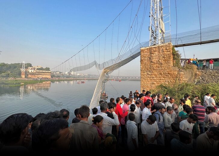 People gather as rescuers search for survivors after a suspension bridge collapsed in Morbi town