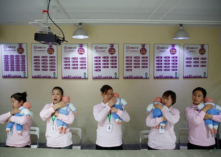 FILE PHOTO: Students at Ayi University, a training program for domestic helpers, practice on baby dolls during a course teaching childcare in Beijing