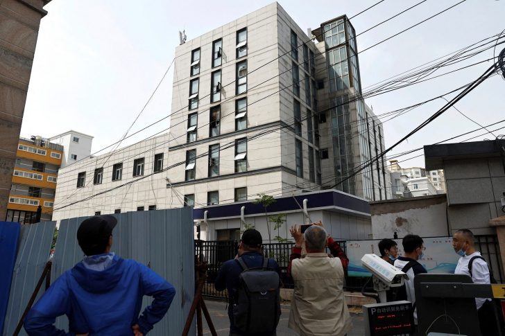 People look at a building with damaged windows following a fire at the Changfeng Hospital, in Beijing