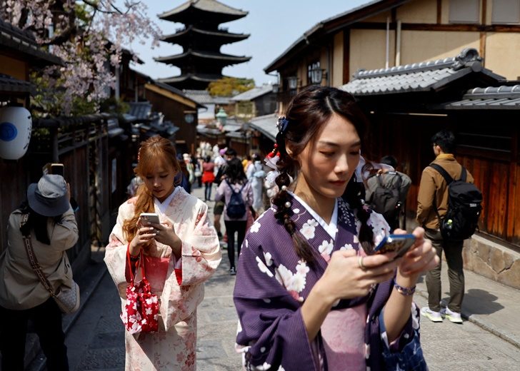 A crowd of tourists walk on the street near Kiyomizu-dera temple in Kyoto