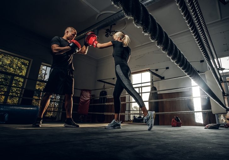 Blonde girl has a training with experienced boxer