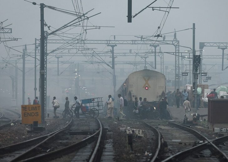 People cross railway tracks on a smoggy morning in New Delhi