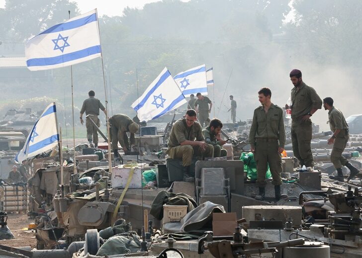Israeli soldiers stand on tanks, near the Israel-Gaza border