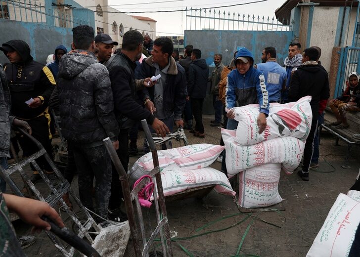 Palestinians gather to receive bags of flour distributed by UNRWA, in Rafah