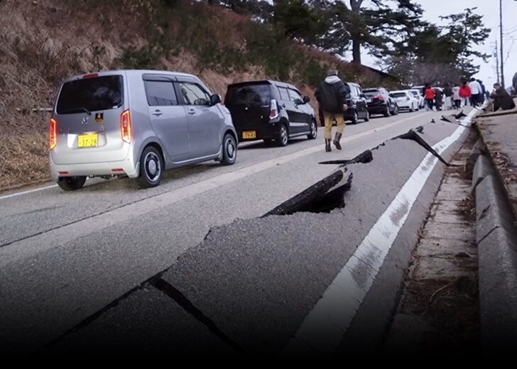 People walk along a road damaged by an earthquake, in Wajima
