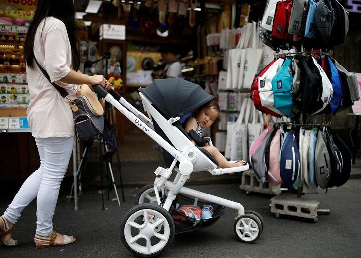 FILE PHOTO: A woman pushing her baby in a stroller shops in the Hongdae area of Seoul