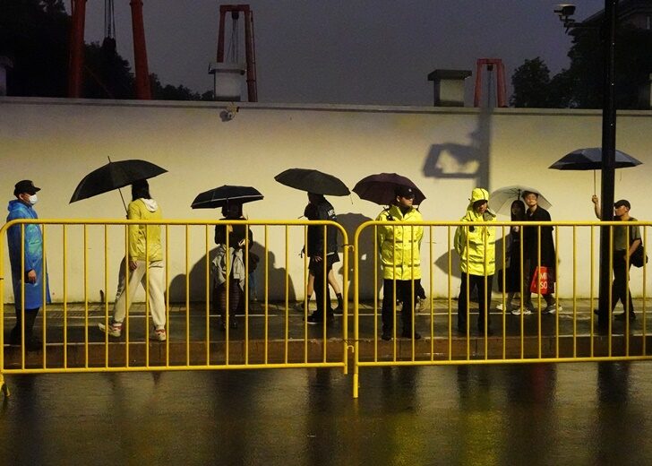 Police officers keep watch near barricades set up along a road in Shanghai