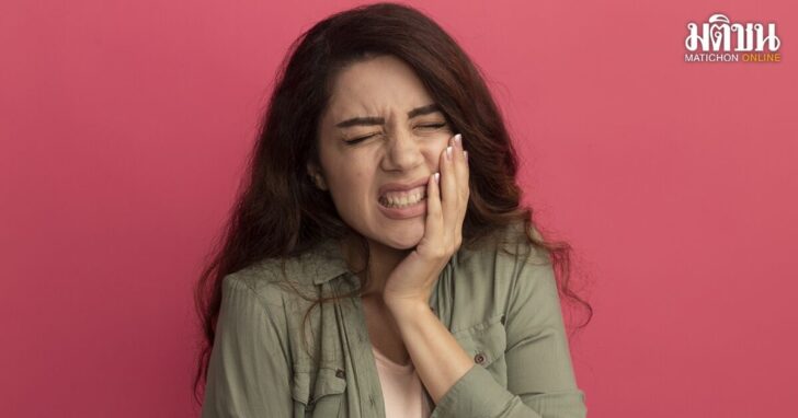 aching young beautiful girl wearing olive green t-shirt putting hand on aching tooth isolated on pink background