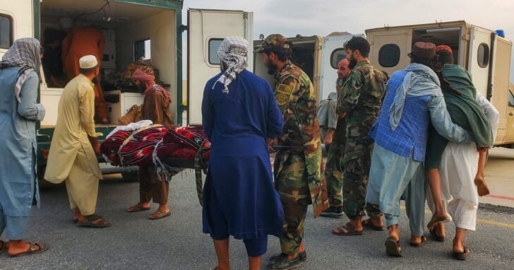Taliban soldiers and civilians carry earthquake victims to an ambulance at an airport in Jalalabad