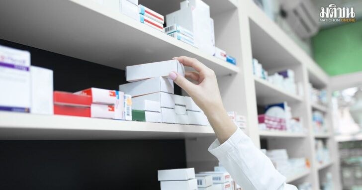 Closeup view of pharmacist hand taking medicine box from the shelf in drug store.