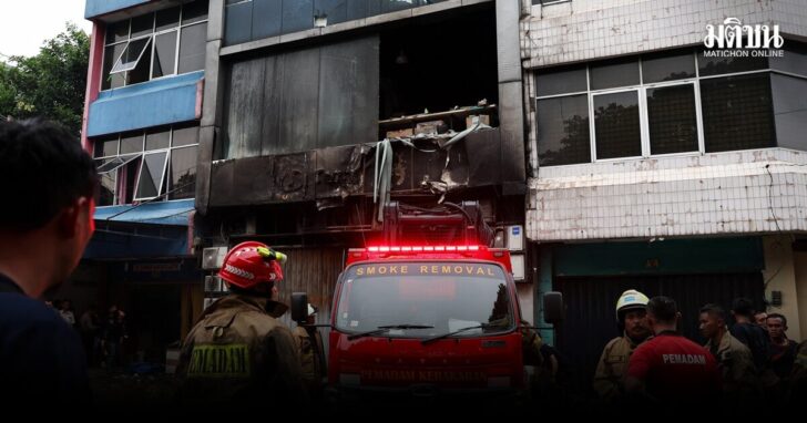 Firefighters stand near a seven-storey building damaged by fire, in Jakarta