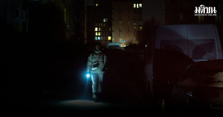 A man carries a torch as he walks in a dark street in a neighbourhood with an electricity outage in Kyiv