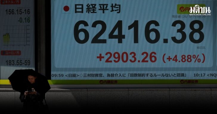 A pedestrian stands in front of a stock quotation board showing the Nikkei share average outside a brokerage in Tokyo
